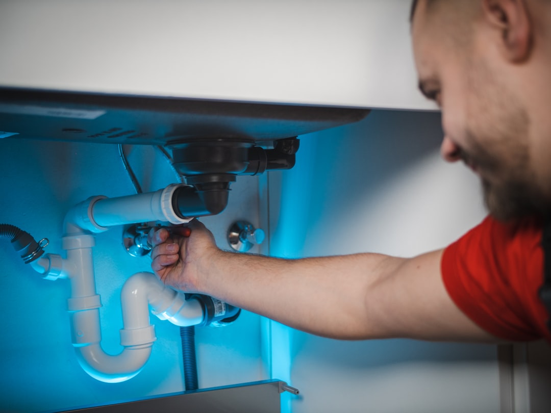 Plumber working on residential piping, representing plumbing company marketing. Photo by Timur Shakerzianov on Unsplash.