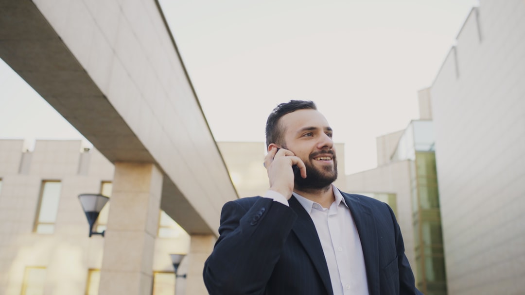 Business professional using a phone outside a modern office, representing customer calls from local search. Photo by Vitaly Gariev on Unsplash.