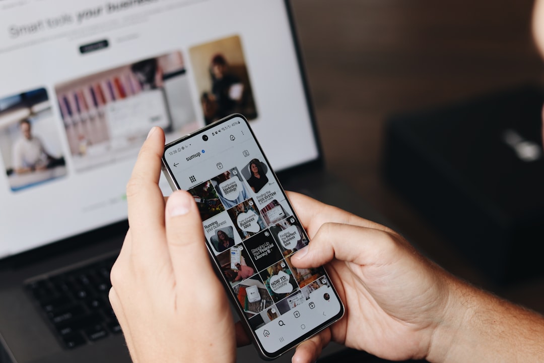 Business owner using social media on a smartphone and laptop, representing social media monetization. Photo by SumUp on Unsplash.